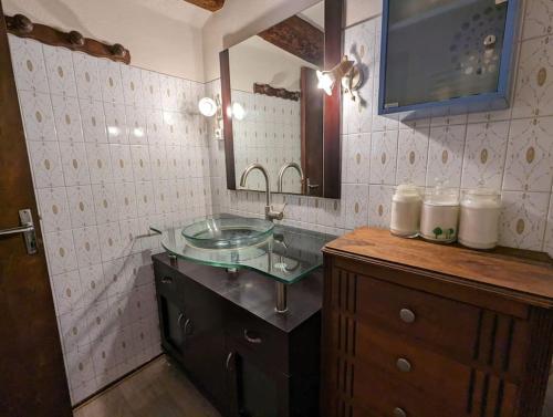 uma casa de banho com um lavatório de vidro e um espelho. em Grande maison de village em Villedaigne