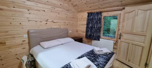a small bedroom with a white bed and a window at Aslan Dağ Evleri in Uzungöl