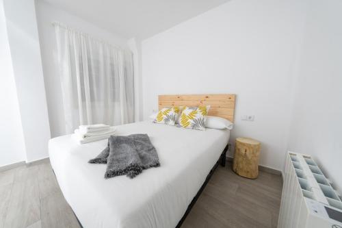 a white bedroom with a large bed with a wooden headboard at Apartamento Marea Viva in Fisterra