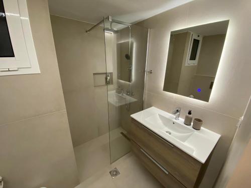 bagno bianco con lavandino e doccia di Hotel Pavlos - Studios a Tolo