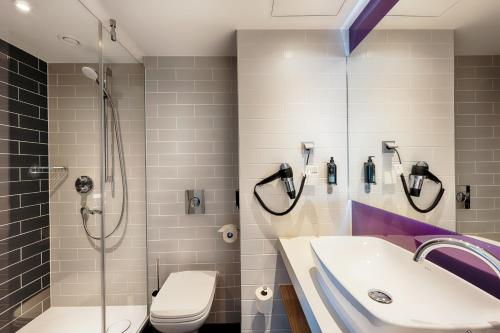 a bathroom with a shower and a sink and a toilet at Premier Inn Leipzig City Hahnekamm in Leipzig