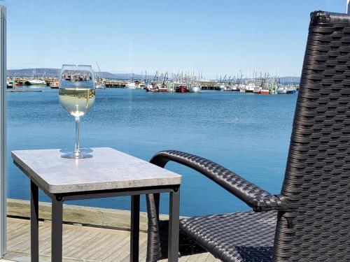 a glass of wine sitting on a table with a chair at Dockside Suites in Digby