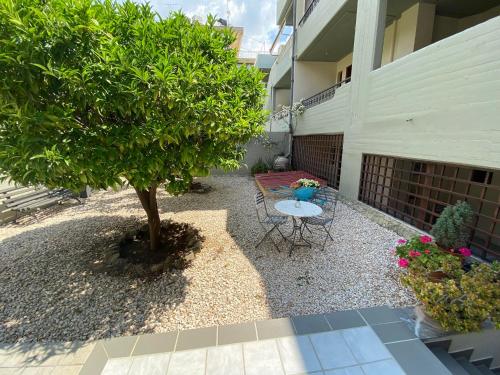 a patio with a table and a tree in front of a building at Hotel Pavlos - Studios in Tolo
