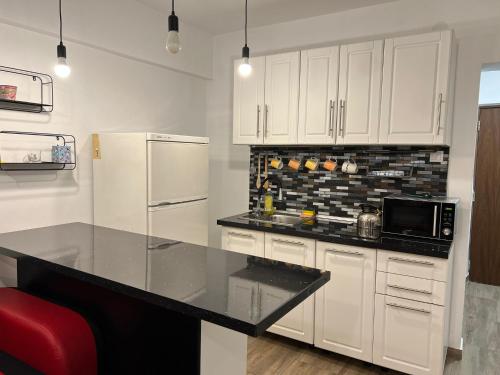 ブカレストにあるFirst Studioの白いキャビネットと黒いカウンタートップを備えたキッチン
