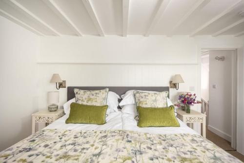 a bedroom with a large bed with green pillows at Mariners Cottage in Mousehole