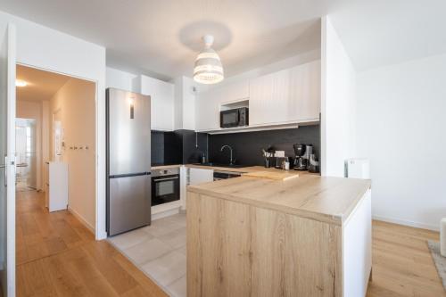 - une cuisine avec des placards blancs et un îlot en bois dans l'établissement Full House By Plaza, à Chessy