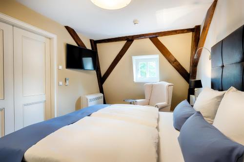 a bedroom with a large bed and a chair at Welcome Hotel Bad Arolsen in Bad Arolsen