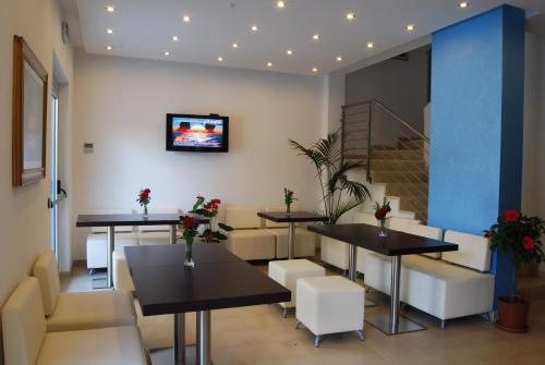 un restaurante con mesas y sillas y TV en la pared en Residence Helene, en Tortoreto Lido