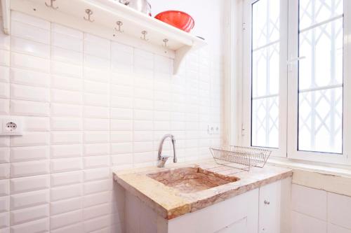 uma cozinha branca com um lavatório e uma janela em Historical Apartment em Lisboa