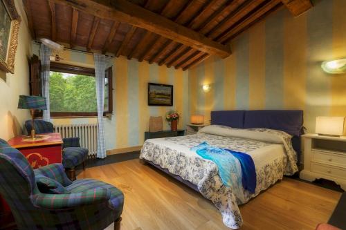 a bedroom with a bed and two chairs and a window at PODERE SANTA CROCE 10, Emma Villas in Radicondoli