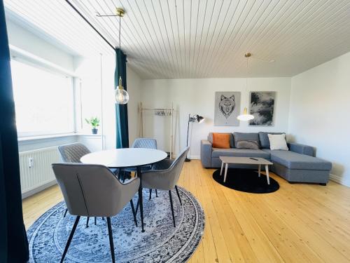 a living room with a couch and a table and chairs at aday - Modern charming apartment in Noerresundby in Nørresundby
