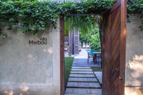 an entrance to a yard with a wooden door at Villa Merbau - Luxury Tropical Private Pool Villa in Gili Islands