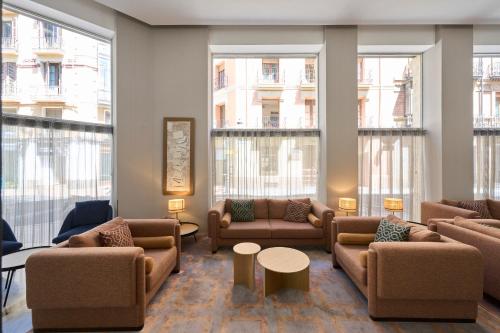 eine Lobby mit Sofas, Tischen und großen Fenstern in der Unterkunft Catalonia El Pilar in Saragossa