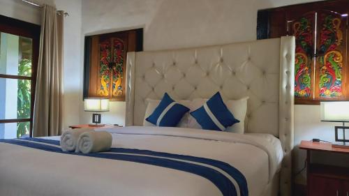 a bedroom with a large bed with blue and white pillows at Matahari Inn Kuta Lombok in Kuta Lombok