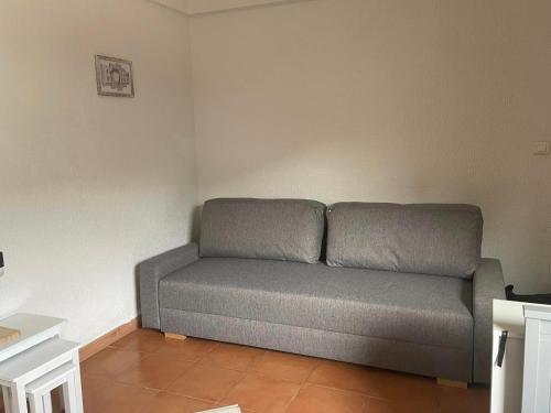 - un canapé gris dans une chambre avec un mur dans l'établissement STUDIO COSY AURON, à Auron