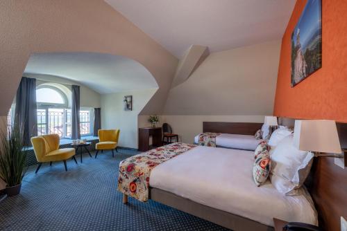 サン・ティポリットにあるHôtel Val-Vignes Colmar Haut-Koenigsbourg, The Originals Relaisのベッドとデスクが備わるホテルルームです。