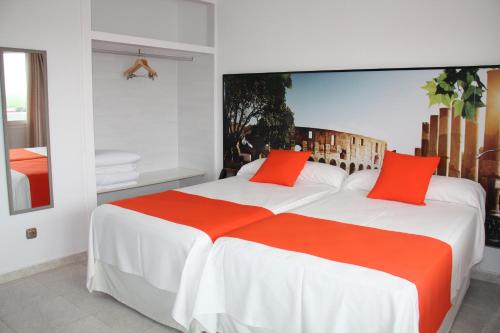 - une chambre avec 2 lits et des oreillers orange dans l'établissement Hacienda Guadalquivir, à Cordoue