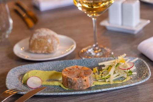 a plate of food on a table with a glass of wine at Hôtel Val-Vignes Colmar Haut-Koenigsbourg, The Originals Relais in Saint-Hippolyte