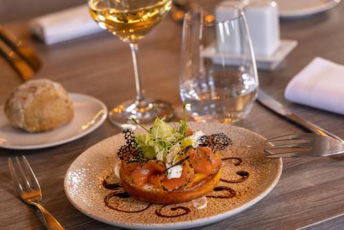 a plate of food on a table with a glass of wine at Hôtel Val-Vignes Colmar Haut-Koenigsbourg, The Originals Relais in Saint-Hippolyte
