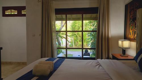 a bedroom with a bed and a large window at Matahari Inn Kuta Lombok in Kuta Lombok