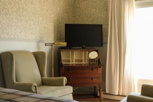 a living room with a tv on a dresser with a chair at The Cooper's Inn in Shelburne