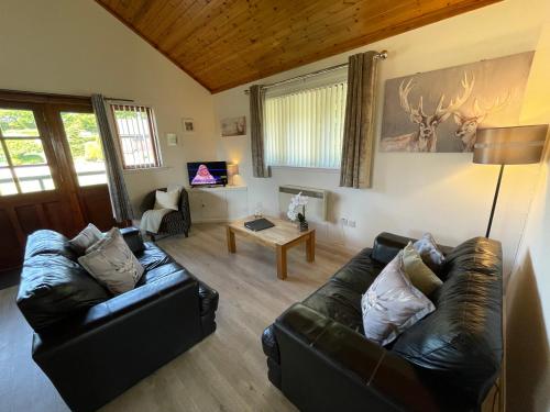 a living room with two leather couches and a table at Wellsfield Farm Holiday Lodges in Stirling