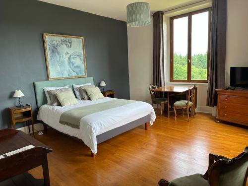 a bedroom with a bed and a table and a window at Domaine LES OURGEAUX in Pagéas