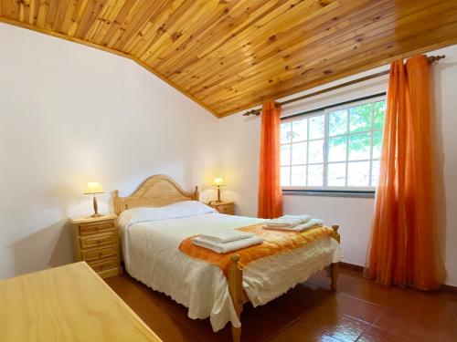 1 dormitorio con 1 cama y una ventana con cortinas de color naranja en Casa da Risca, en Unhais da Serra