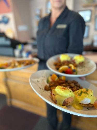 a person holding three plates of food on a counter at Admiral Digby Inn Restaurant and Cottages in Digby
