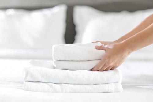 a woman is stacking towels on a bed at Luxurious Apartment Just Off Mill Rd in Cambridge