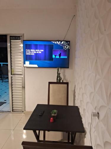 una mesa y una silla con TV en la pared en Minha casa sua casa completa, en Guarulhos