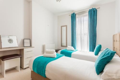 two beds in a bedroom with blue curtains at Castle Haven Apartment, Redhill in Redhill