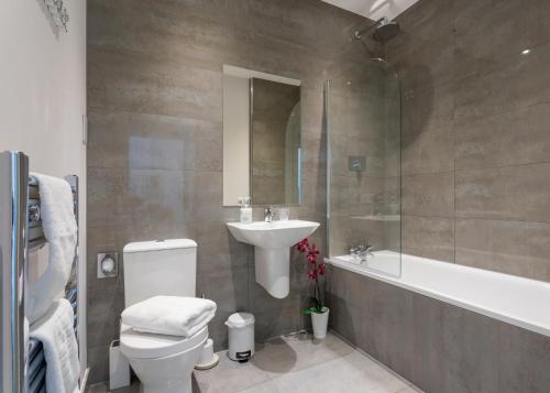 a bathroom with a toilet and a sink and a bath tub at Castle Haven Apartment, Redhill in Redhill