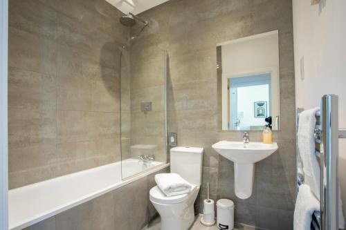 a bathroom with a toilet and a sink and a shower at Queens Lodge, Redhill in Redhill