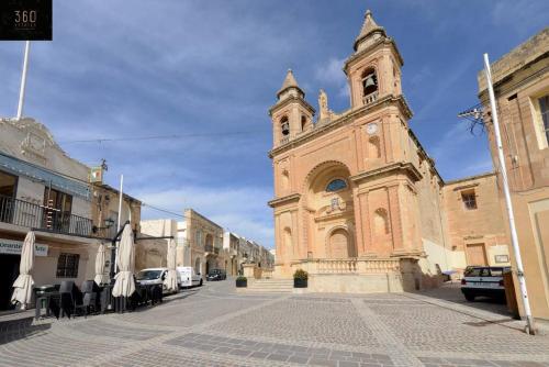 a large building with a clock tower on a street at Designer 3BR home, w/ lovely green views & WIFI by 360 Estates in Marsaxlokk