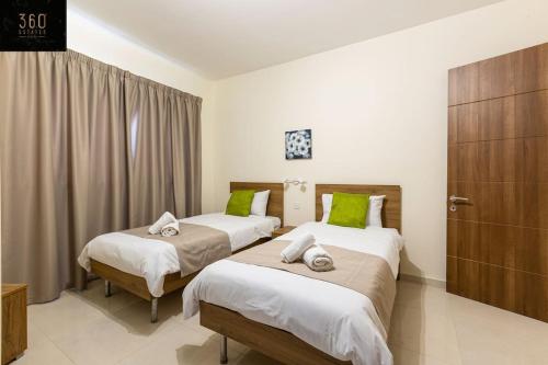 a bedroom with two beds with green pillows at Designer 3BR home, w/ lovely green views & WIFI by 360 Estates in Marsaxlokk