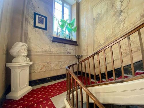 un escalier dans un bâtiment avec une statue dans l'angle dans l'établissement Prieuré de la Chesnaie x Melrose, à Saint-Vigor-le-Grand