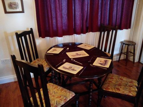 a dining room table with chairs and a red curtain at Flo's Cottage self-catering in Newark upon Trent