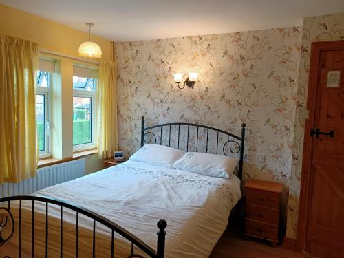 a bedroom with a bed with white sheets and floral wallpaper at Flo's Cottage self-catering in Newark-on-Trent