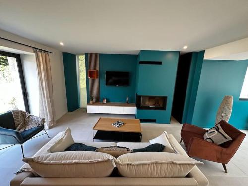 ein Wohnzimmer mit blauen Wänden, einem Sofa und Stühlen in der Unterkunft Charmante longère à 700 m de la plage in Guidel