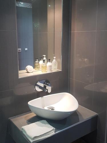 La salle de bains est pourvue d'un lavabo blanc et d'un miroir. dans l'établissement Powis Cottage, à Laugharne