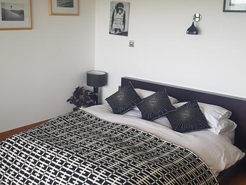 a bed with black and white sheets and pillows at Powis Cottage in Laugharne
