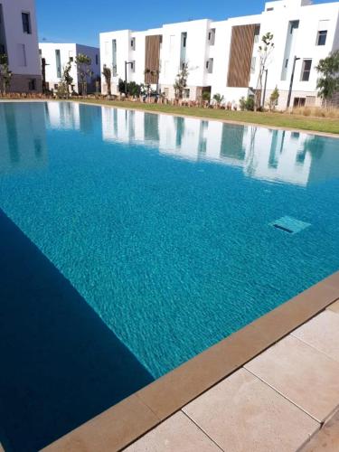 a large blue swimming pool in front of a building at Bel Appartement Agadir Tamourit in Agadir