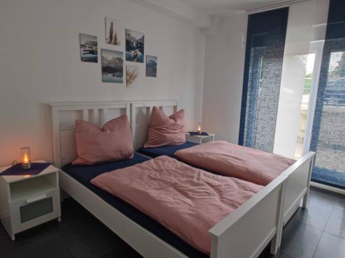 two beds in a bedroom with pink sheets and pillows at Moers City Apartments in Moers
