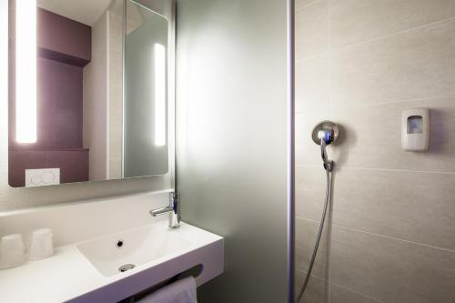 een badkamer met een douche, een wastafel en een spiegel bij B&B HOTEL Cluses Sud in Cluses