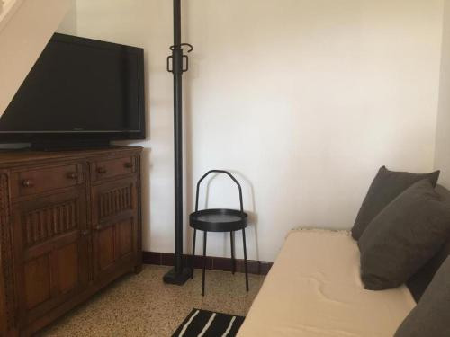 a living room with a couch and a television on a dresser at Maison Blanche in Laroque-des-Albères