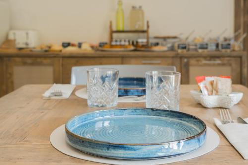 a wooden table with a blue plate and glasses on it at BnB Il Grecale in Lacona