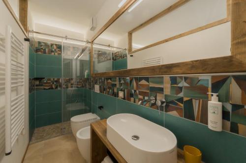 a bathroom with a white toilet and green tiles at BnB Il Grecale in Lacona