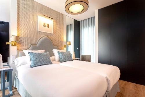 a bedroom with a large white bed with blue pillows at Genteel Home Betis 67 in Seville