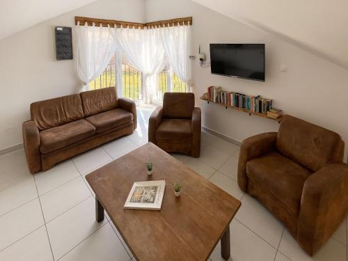 a living room with a couch and two chairs and a table at Tanyacsárda Panzió in Baja